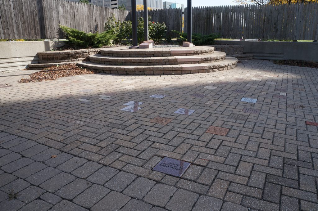 Large brick paver patio with curved stone steps and raised landscaping walls.